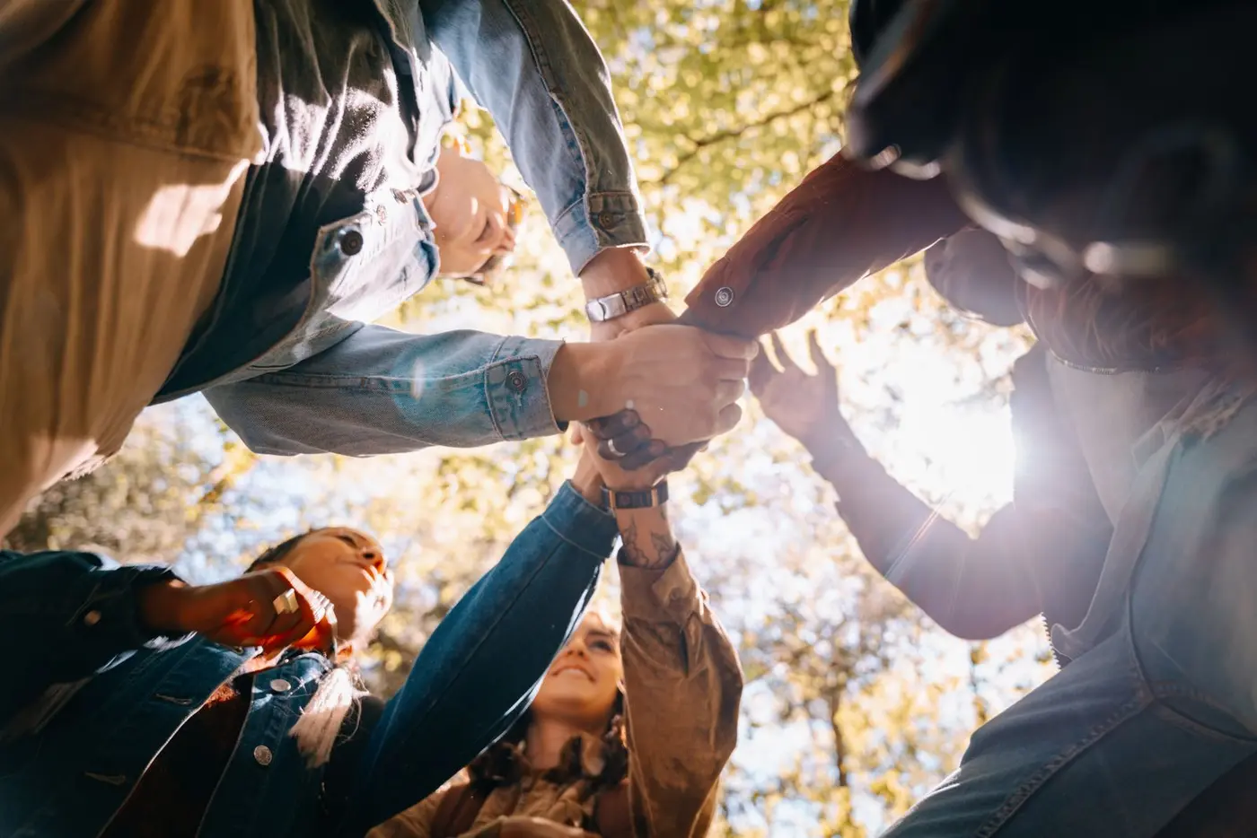A diverse group joining hands outdoors